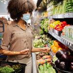 Woman wearing a mask in the vegetable aisle of a market.