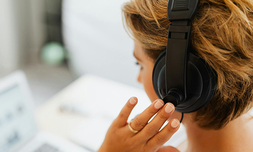 woman wearing headphones while looking at computer