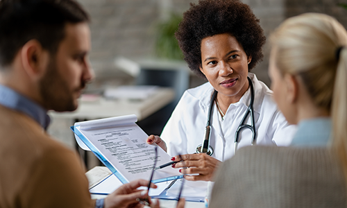 Doctor discussing a document with couple.