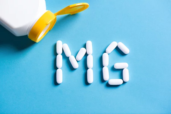 Magneisum pills arranged in the letters MG next to a bottle.