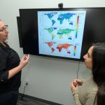 Veterin and student in front of a screen showing research